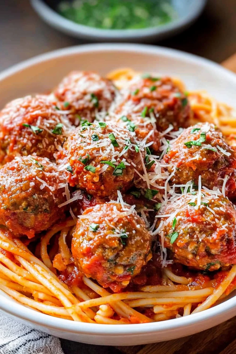 A delicious plate of Italian meatballs served over spaghetti, topped with fresh parmesan cheese and garnished with basil.